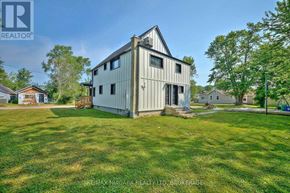 Fort Erie (Lakeshore) duplex for rent - A large, two-story house with a sloped roof and a garage is situated in a grassy yard.