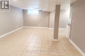 Toronto (Woburn) apartment for rent - A spacious room with beige tiled flooring and white walls, with a window and a pillar in the middle.