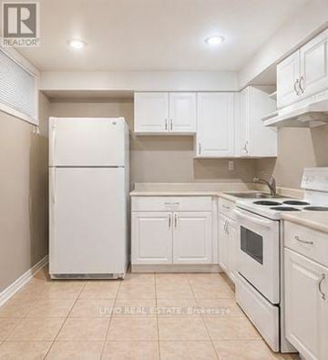 Toronto (Woburn) apartment for rent - A white refrigerator stands in a kitchen with white cabinets and a white stove.