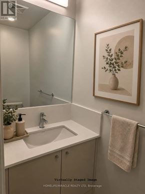 Toronto (Regent Park) condo for rent - A bathroom with a sink, mirror, and a picture of a plant in a vase.