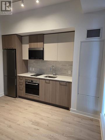 Toronto (Regent Park) condo for rent - A kitchen with wooden cabinets and a black fridge.