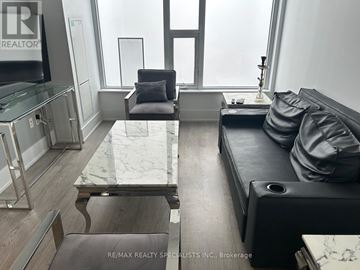 Toronto (Waterfront Communities) condo for rent - A modern living room with a black couch and a glass coffee table.