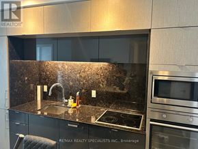 Toronto (Waterfront Communities) condo for rent - A modern kitchen with a granite countertop and stainless steel appliances.