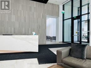 Mississauga (City Centre) condo for rent - A reception area with a white reception desk and a grey couch.