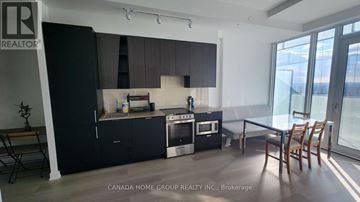 Mississauga (City Centre) condo for rent - A modern kitchen with black cabinets and a dining table.