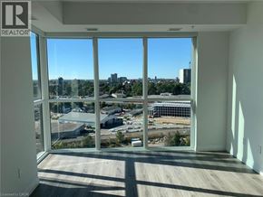 Kitchener condo for rent - A room with a large window overlooking a cityscape.