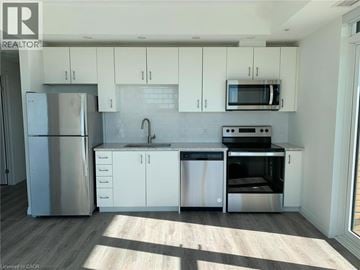 Kitchener condo for rent - A kitchen with white cabinets and stainless steel appliances.
