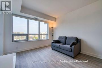 Markham (Commerce Valley) condo for rent - A living room with a grey couch and a large window.