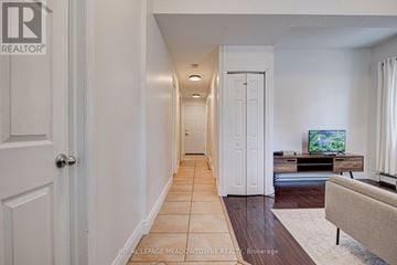 Guelph (Downtown) multi-family for rent - A hallway with a door on the left and a living room with a couch and television on the right.