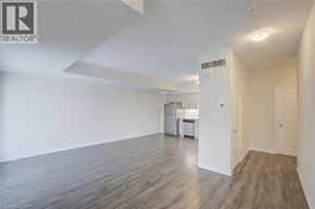 Kitchener townhouse for rent - A spacious room with wooden flooring and white walls.