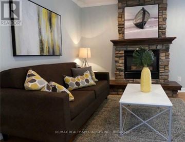 Barrie (Edgehill Drive) duplex for rent - A living room with a brown couch, a yellow vase, and a painting of a boat on the wall.