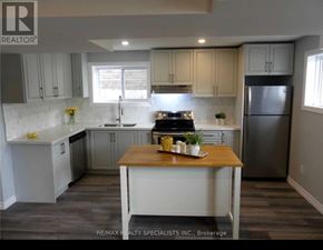 Barrie (Edgehill Drive) duplex for rent - A kitchen with a table in the middle and a refrigerator on the right.