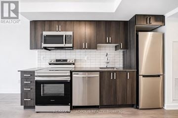 Pickering (Bay Ridges) condo for rent - A modern kitchen with dark wood cabinets and stainless steel appliances.