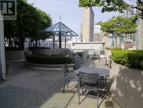 Toronto (Waterfront Communities) condo for rent - A patio with a table and chairs is in front of a tall building.