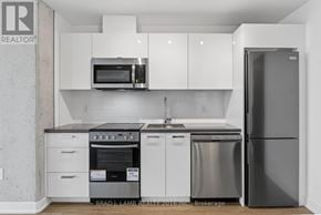 Toronto (Moss Park) condo for rent - A kitchen with white cabinets and a stainless steel refrigerator.