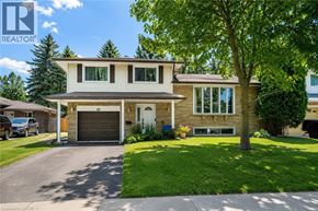 Kitchener apartment for rent - A two-story house with a garage is surrounded by greenery and a clear sky.