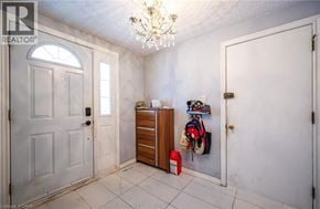 Kitchener apartment for rent - A chandelier hangs from the ceiling in a white room with a door and a wooden cabinet.