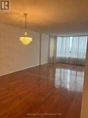 Vaughan (Brownridge) condo for rent - A room with wooden floors and a chandelier hanging from the ceiling.