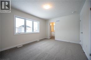 Kitchener apartment for rent - A well lit bedroom with a large window and a carpeted floor.