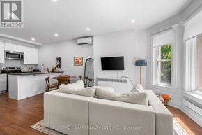 Toronto (Roncesvalles) multi-family for rent - A modern living room with a white couch and a flat screen TV mounted on the wall.