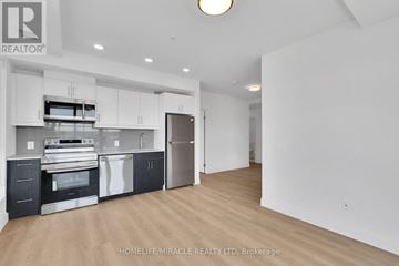 Kitchener condo for rent - A spacious kitchen with white cabinets and a wooden floor.