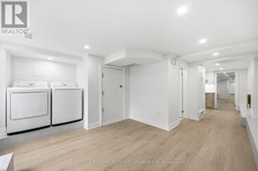 Toronto (South Parkdale) apartment for rent - A spacious, empty room with a kitchenette and hardwood floors.