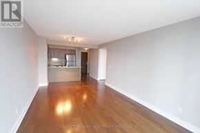 Toronto (Bay Street Corridor) condo for rent - A spacious room with wooden floors and a kitchen area in the background.
