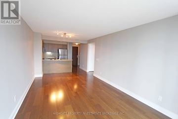 Toronto (Bay Street Corridor) condo for rent - A spacious room with wooden floors and a kitchen area in the background.