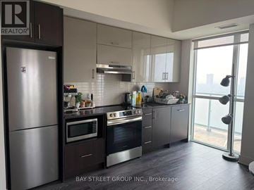 Toronto (Don Valley Village) condo for rent - A modern kitchen with a refrigerator and stove top oven.