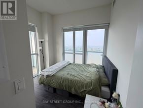 Toronto (Don Valley Village) condo for rent - A bedroom with a bed and a window overlooking the city.