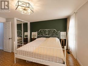 Toronto (Etobicoke West Mall) townhouse for rent - A bedroom with a white bed and a chandelier.