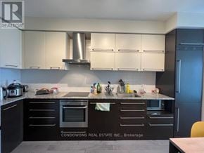 Toronto (Bay Street Corridor) condo for rent - A kitchen with black cabinets and a stainless steel range hood.