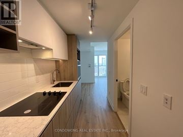 Toronto (Moss Park) condo for rent - A kitchen with a black stove top oven and white countertops.