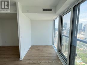 Toronto (Moss Park) condo for rent - A room with a window overlooking a cityscape.