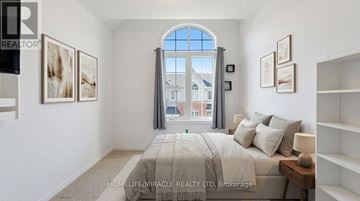 Orangeville townhouse for rent - A bedroom with a large bed and a window with a view of a building outside.
