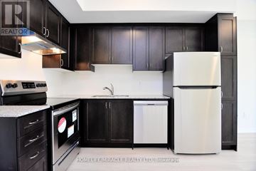 Toronto (Eglinton East) townhouse for rent - A kitchen with black cabinets and a white fridge.