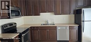 Kitchener townhouse for rent - A kitchen with brown cabinets and a white dishwasher.
