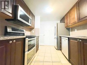 Toronto (Bay Street Corridor) condo for rent - A kitchen with brown cabinets and a white refrigerator.