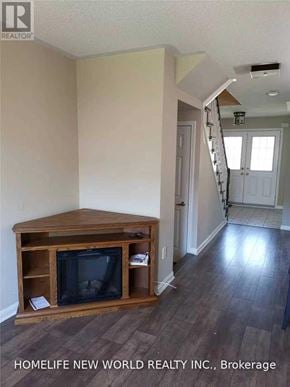 Markham (Cornell) townhouse for rent - A living room with a wooden entertainment center and a staircase in the background.