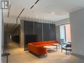Toronto (North St. James Town) condo for rent - A modern living room with a large orange sofa and a glass partition wall.