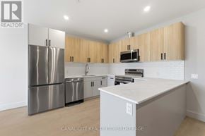 Thorold (Thorold Downtown) apartment for rent - A kitchen with a stainless steel refrigerator, microwave, and wooden cabinets.