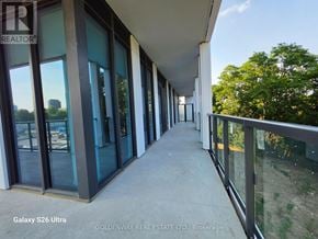 Toronto (Bayview Village) condo for rent - A balcony with glass railings and a view of trees and buildings outside.