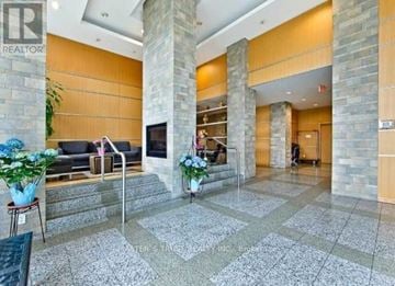 Toronto (Woburn) condo for rent - A lobby with a stone pillar and a glass railing.