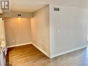 Toronto (Waterfront Communities) condo for rent - A room with wooden flooring and white walls, with a small light on the wall.