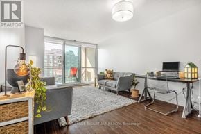 Toronto (Newtonbrook East) condo for rent - A well-lit, modern living room with a grey sofa, a wooden coffee table, and a large window with a view of the city.