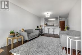 Toronto (Newtonbrook East) condo for rent - A living room with a grey couch, a grey rug, a wooden table, and a white chair.