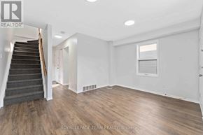 Ottawa apartment for rent - A spacious room with wooden flooring and a staircase leading to another level.