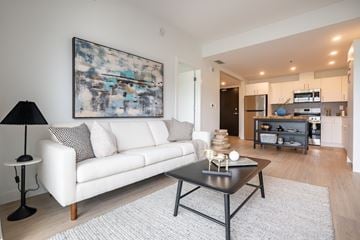 Winnipeg apartment for rent - A modern living room with a white couch and a large abstract painting on the wall.
