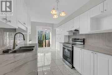 Ottawa townhouse for rent - A modern kitchen with white cabinets and a marble countertop.