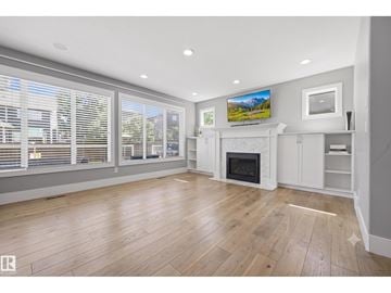 Edmonton apartment for rent - A spacious living room with a fireplace and a television mounted on the wall.